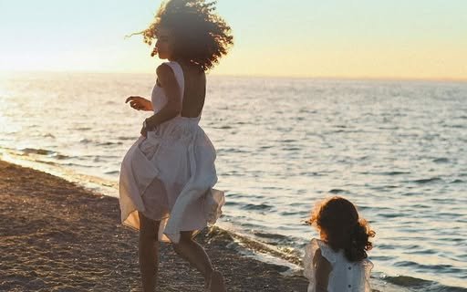 Dos niñas corriendo en la orilla de la playa al atardecer